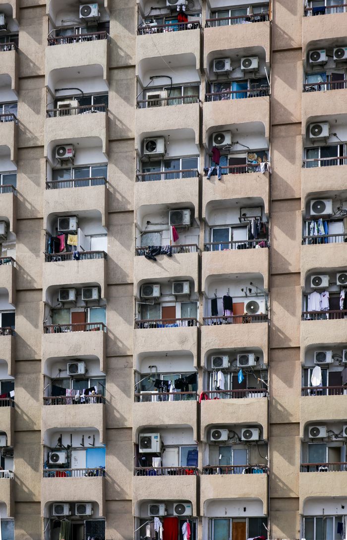 Close-up of a high-rise residential building showcasing multiple balconies with air conditioning units and laundry.